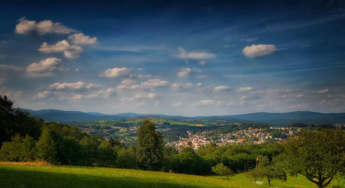 Spring landscape in the Bavarian Forest with meadows, forest and a view over a small town